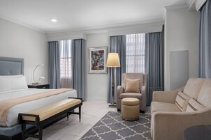 Ein modernes Hotelzimmer mit einem großen Bett, einer Couch, einem Sessel und einem kleinen Tisch.