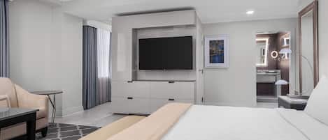 Una habitación de hotel moderna con una cama grande, un televisor de pantalla plana en la pared, un escritorio con una silla y una mesita.