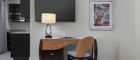 Una habitación de hotel moderna con escritorio, silla, cama, televisión y obras de arte.
