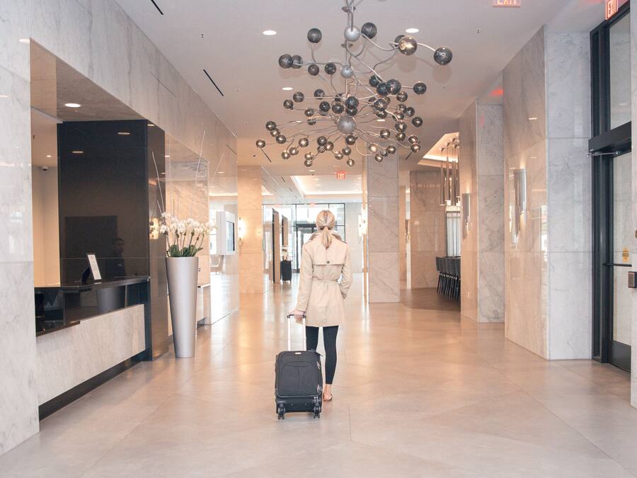 A spacious lobby with a modern chandelier, a reception desk, and a clear exit sign.