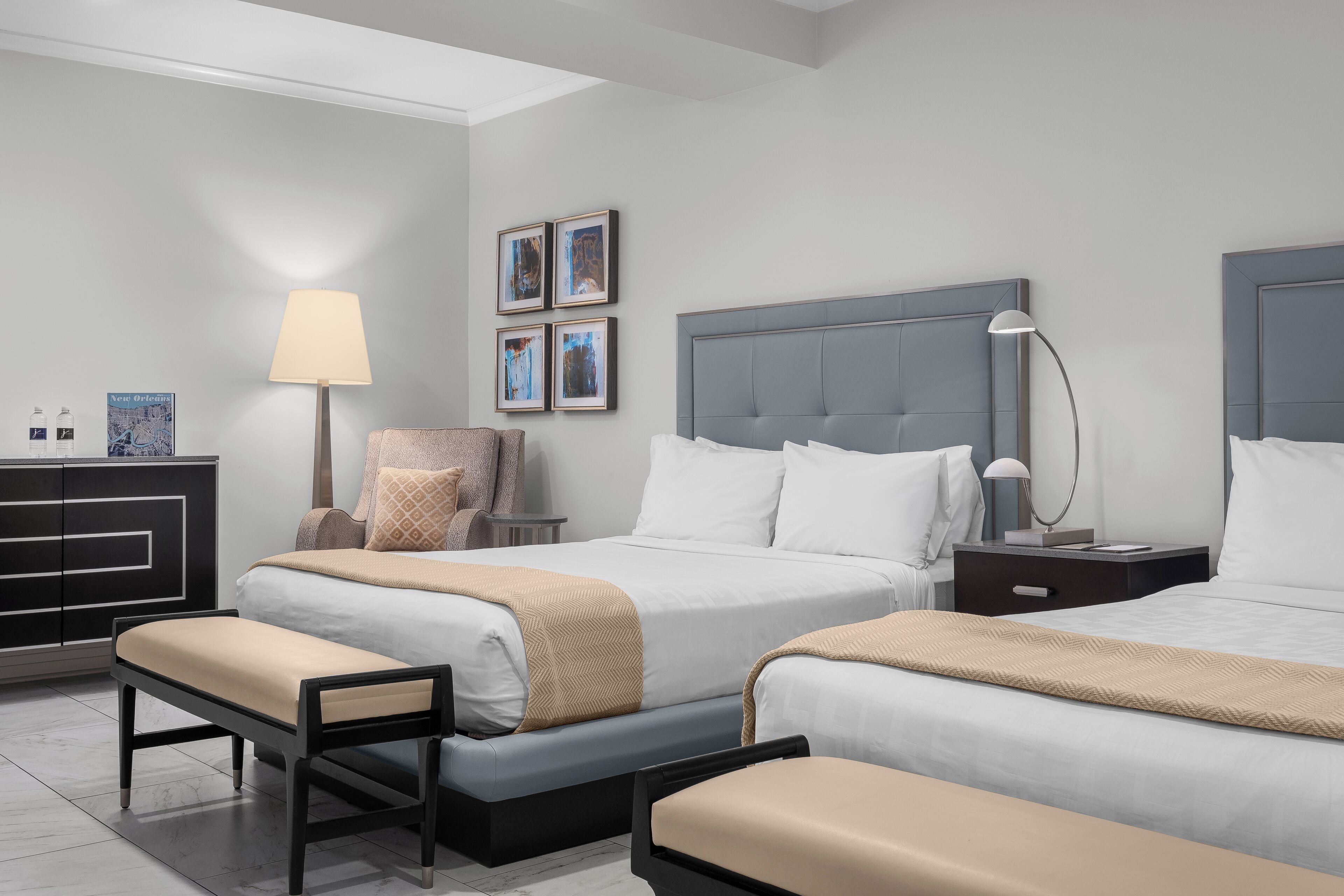Een moderne hotelkamer met twee bedden, een bureau, een stoel en een lamp.