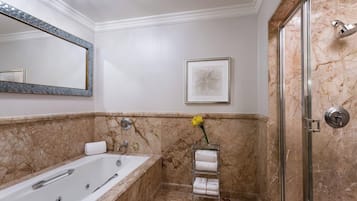 A bathroom with a marble floor, a bathtub, a shower, a glass-towel rack, and a framed artwork on the wall.