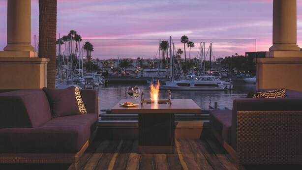 A terrace with a fire feature, seating, and a marina view. - The Ritz-Carlton, Marina del Rey (Marina del Rey)