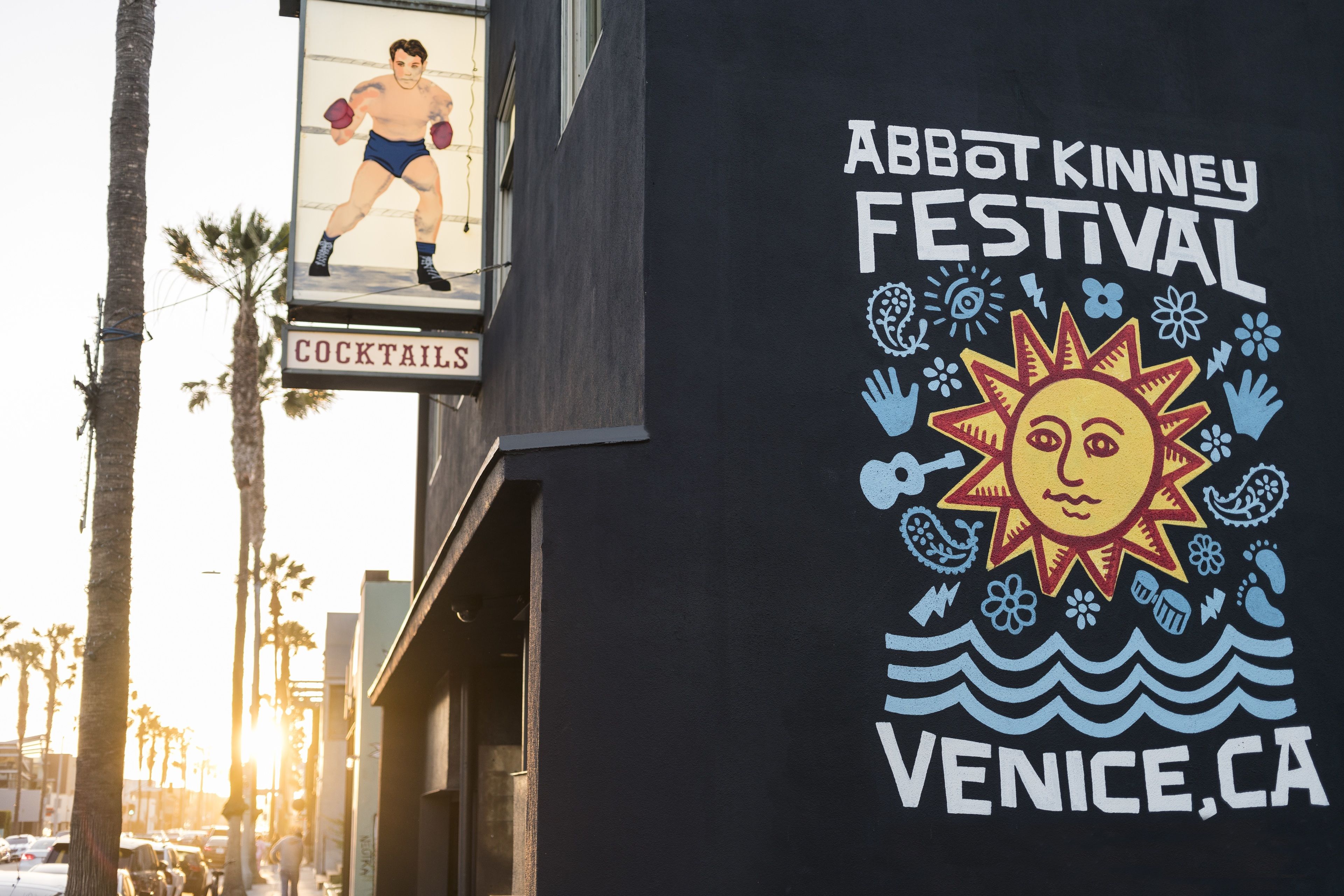 A building with a sign for the Abbot Kinney Festival and a sign for cocktails.