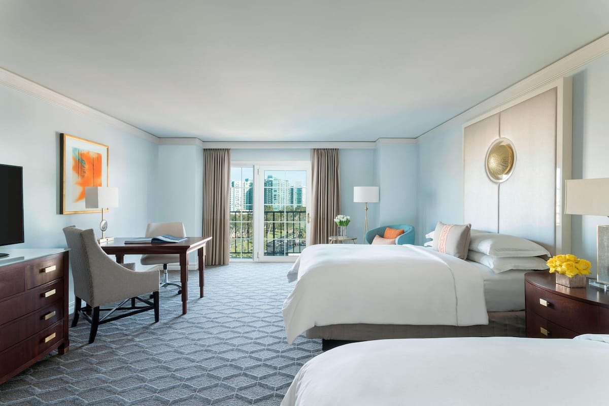 A hotel room with a large bed, a desk, a chair, and a television.