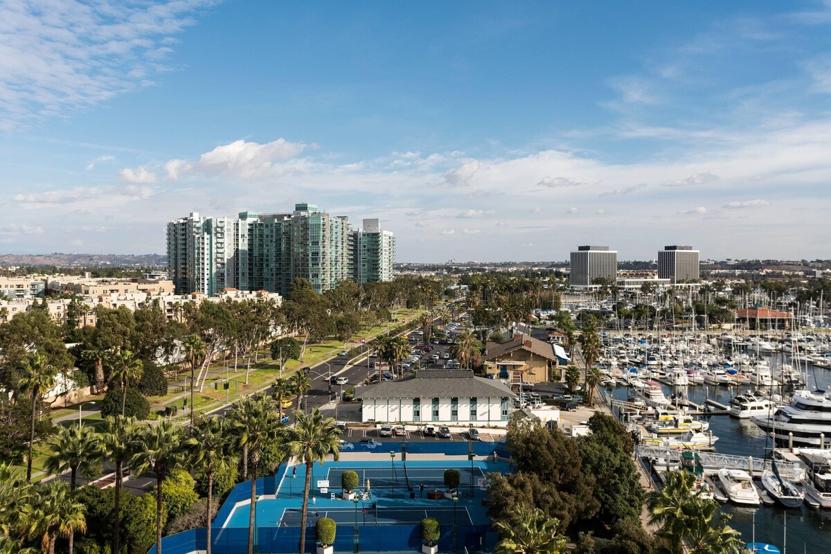A marina with boats, a tennis court, and high-rise buildings in the background.
