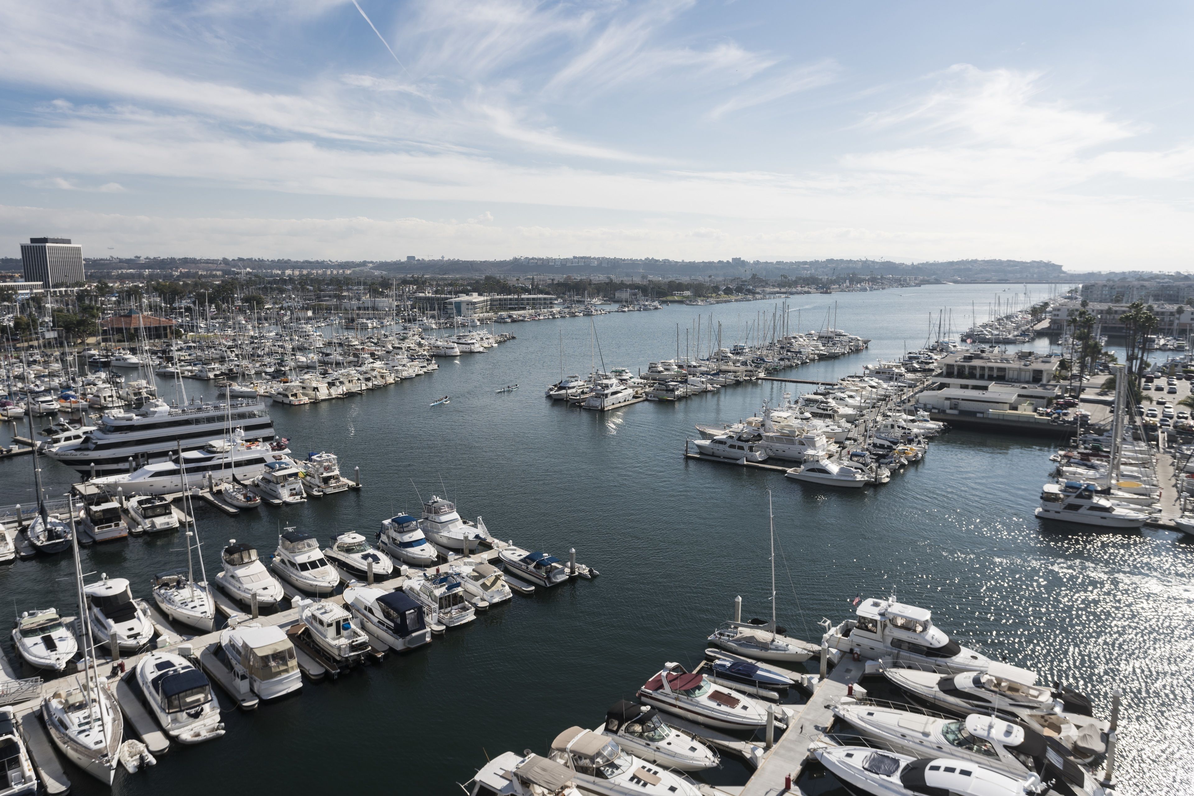 Un port de plaisance où de nombreux bateaux sont amarrés, un ciel dégagé et une vue lointaine sur la ville.