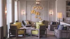 A modern lounge with a central seating area featuring yellow chairs and a sofa, a chandelier, and wall-mounted decorative elements. - The Ritz-Carlton, Marina del Rey (Marina del Rey)