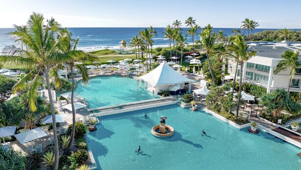 A resort pool with a view of the ocean, surrounded by palm trees and lounge chairs. - Sheraton Grand Mirage Resort, Gold Coast (Main Beach)