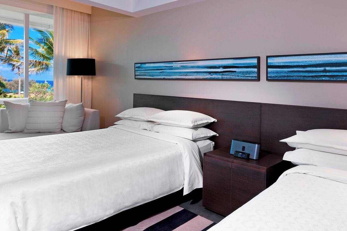 A hotel room with a large bed, a bedside table with a lamp, and two wall-mounted artworks.