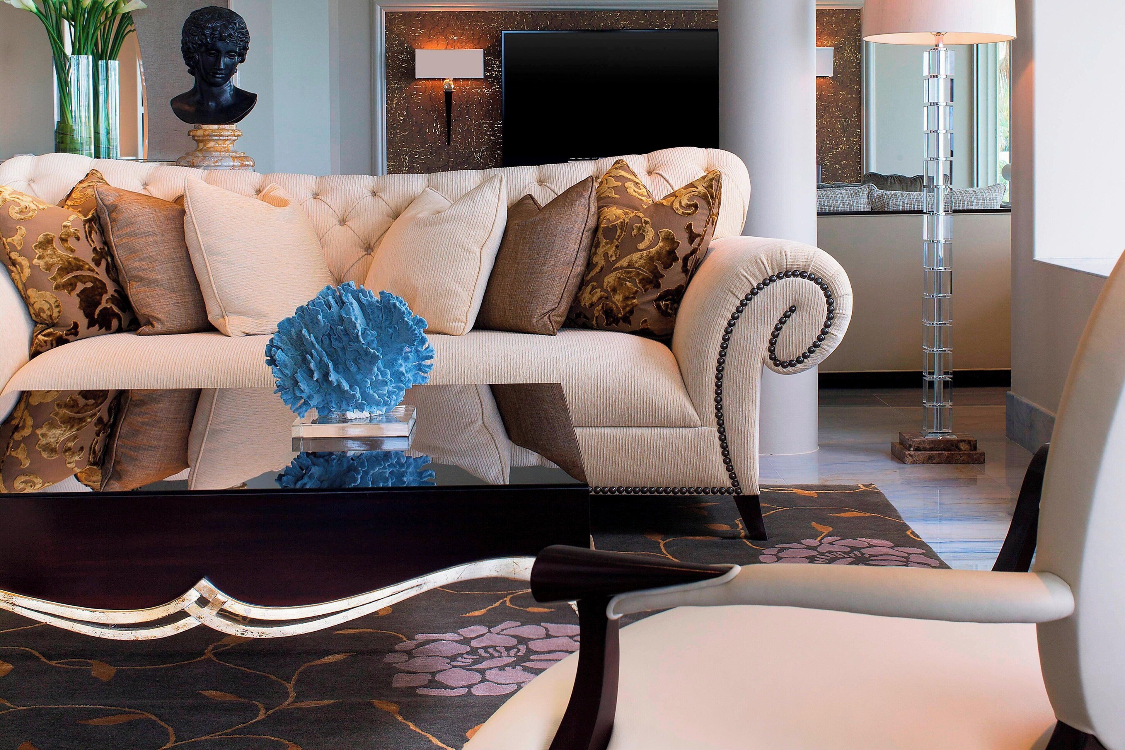 A modern living room with a tufted sofa, decorative pillows, a blue abstract sculpture, and a floor lamp.