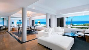 A spacious living area with a large white sofa, a dining table, and chairs, with a view of the ocean. - Sheraton Grand Mirage Resort, Gold Coast (Main Beach)