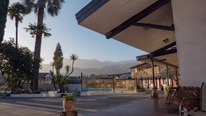 Un hotel con piscina, palmeras y montañas al fondo.