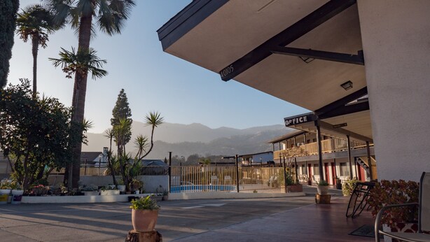A hotel with a pool, palm trees, and mountains in the background.