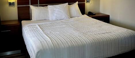 A neatly made bed with a headboard, two bedside lamps, and a wooden nightstand.