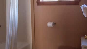 A bathroom with a bathtub, toilet, and a window above the toilet.