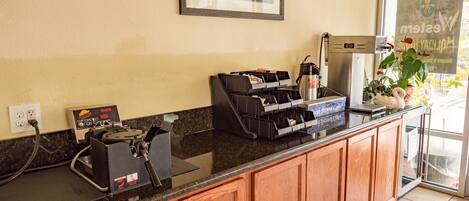 A coffee station with a coffee machine, a grinder, and a display case with coffee pods.
