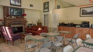 A cozy living area with a fireplace, comfortable seating, and a kitchen area.