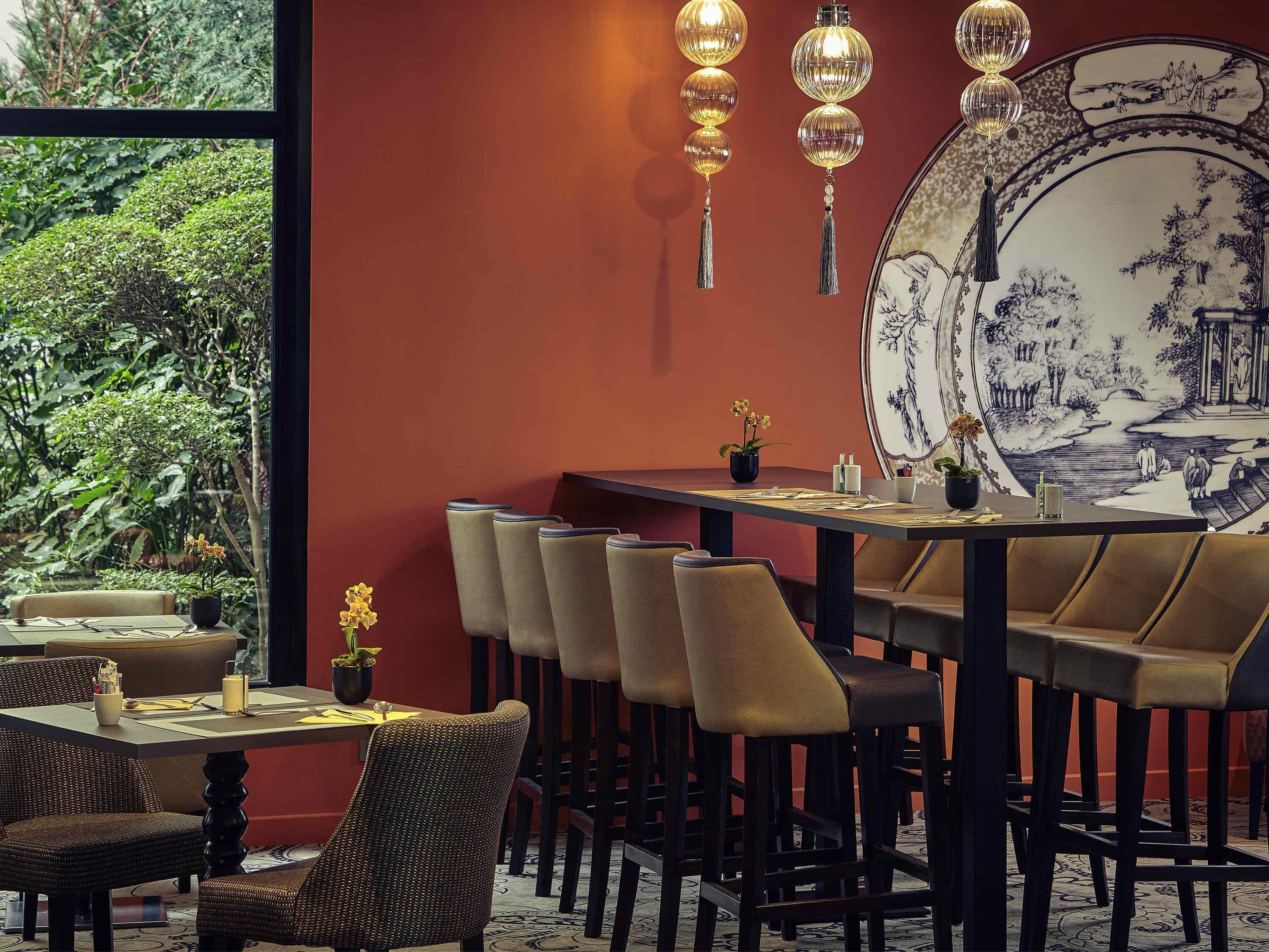 Un restaurante con un comedor que incluye mesas y sillas, un plato decorativo grande en la pared, y lámparas colgantes.