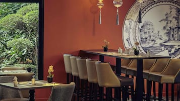Un restaurante con un comedor que incluye mesas y sillas, un plato decorativo grande en la pared, y lámparas colgantes.