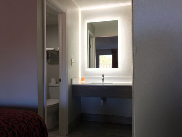 Un baño con lavabo, espejo y retrete.
