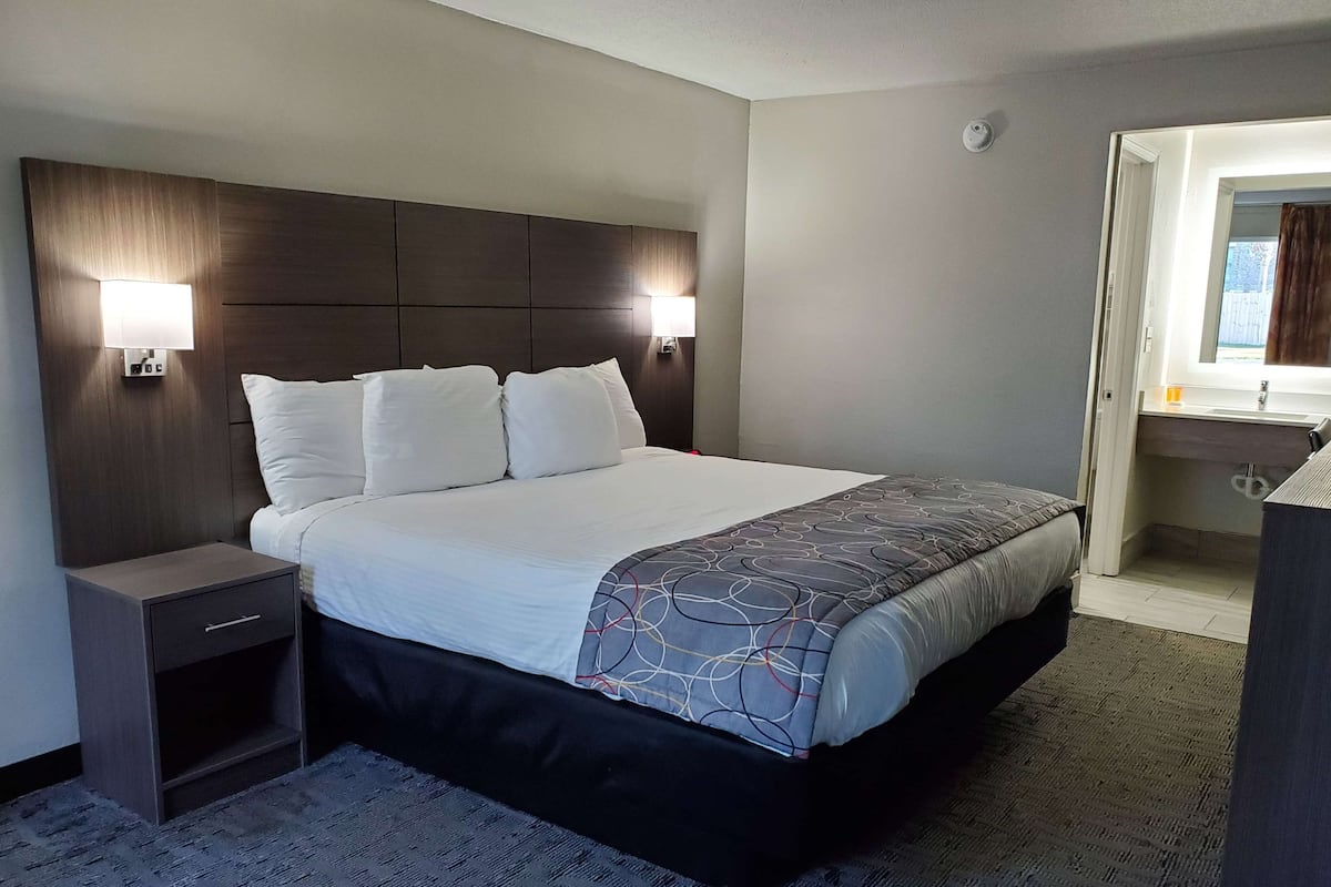 Una habitación de hotel con una cama grande, dos lámparas de noche, una mesita de noche y un escritorio pequeño.