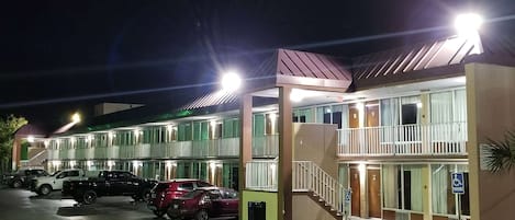 Un motel de varios pisos con estacionamiento, una entrada accesible para personas con discapacidad y una escalera que lleva a los pisos superiores.
