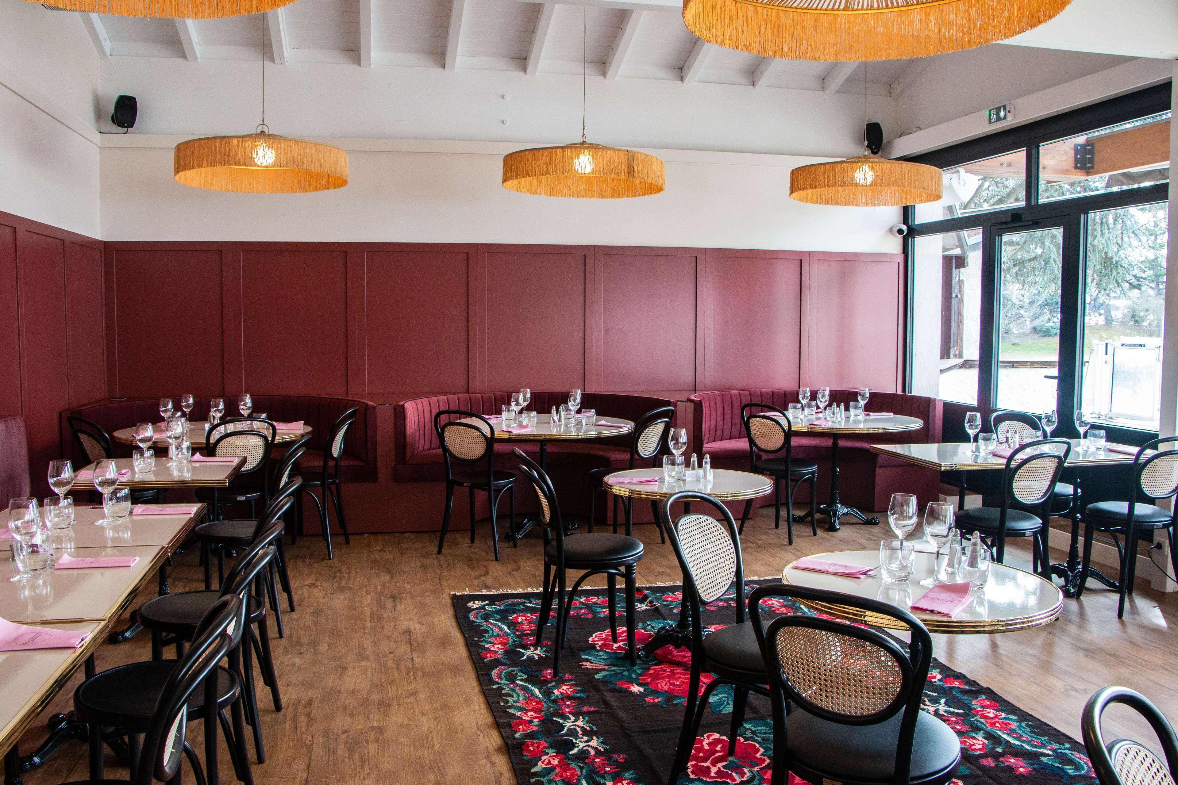 A restaurant interior with booths and tables, wooden floors, and hanging wicker lamps.