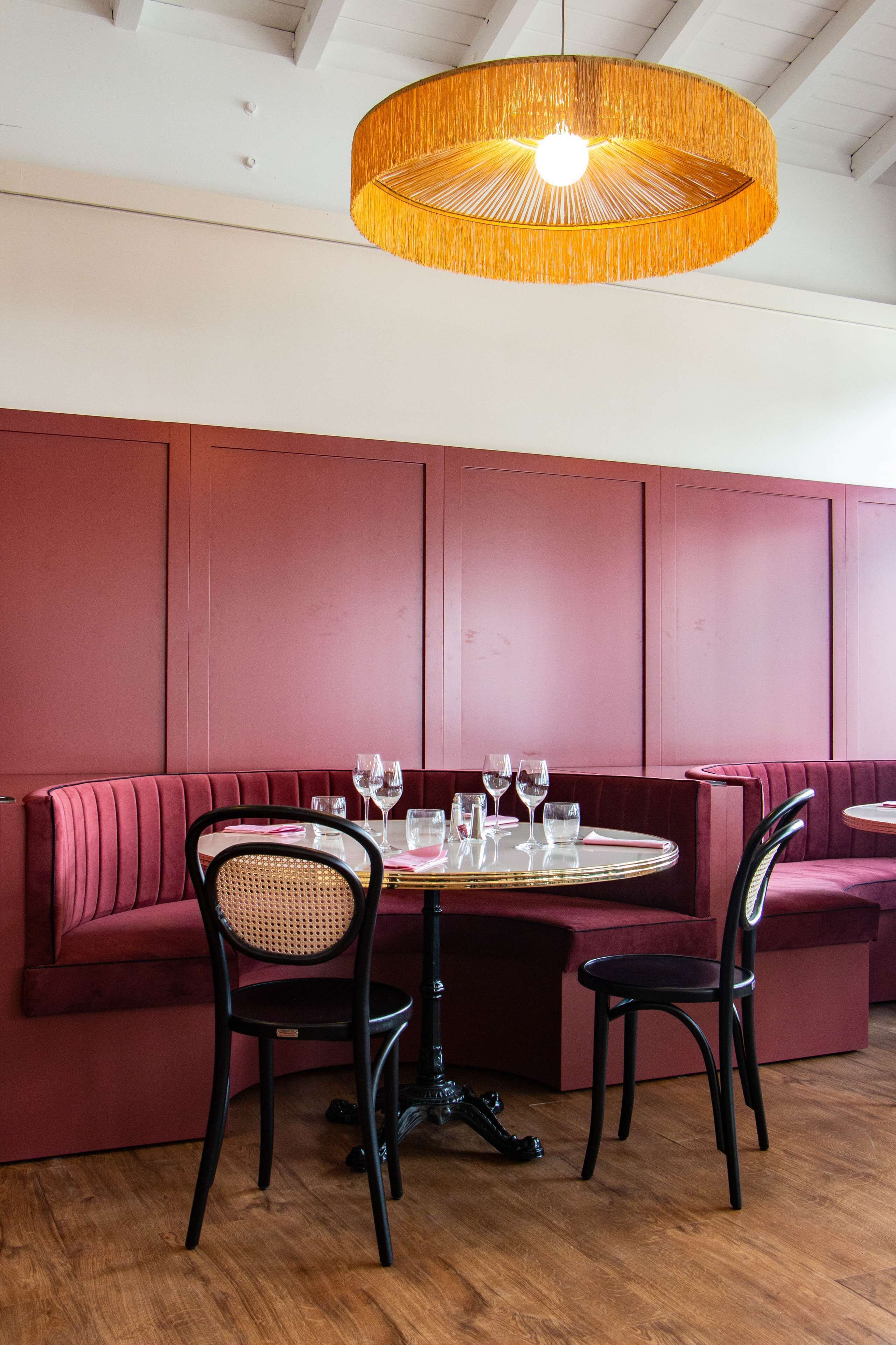 Un coin repas comprenant une table ronde, deux chaises et un banc.