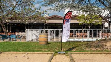 Un patio con cancha de croquet, mobiliario exterior y un edificio con zona de porche techada.