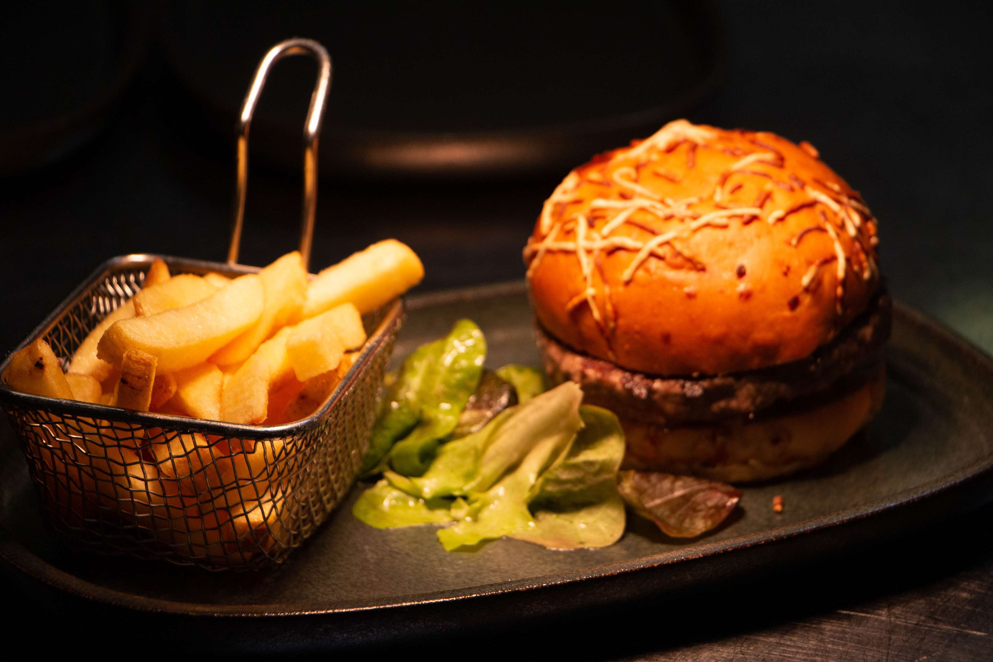 A burger with fries and a side salad on a plate.