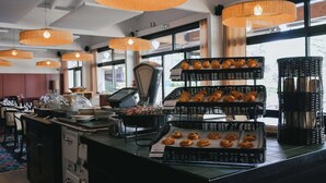 Eine Theke einer Bäckerei mit verschiedenen Backwaren in Korbflexen, einer Kaffeemaschine und einer Kasse.