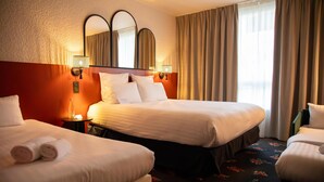 Ein Hotelzimmer mit zwei Betten, einem großen Spiegel und einem floralen Teppich.
