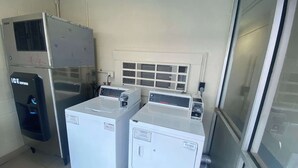 Uma lavanderia com duas máquinas de lavar de abertura frontal, uma secadora empilhada e um aquecedor de água.