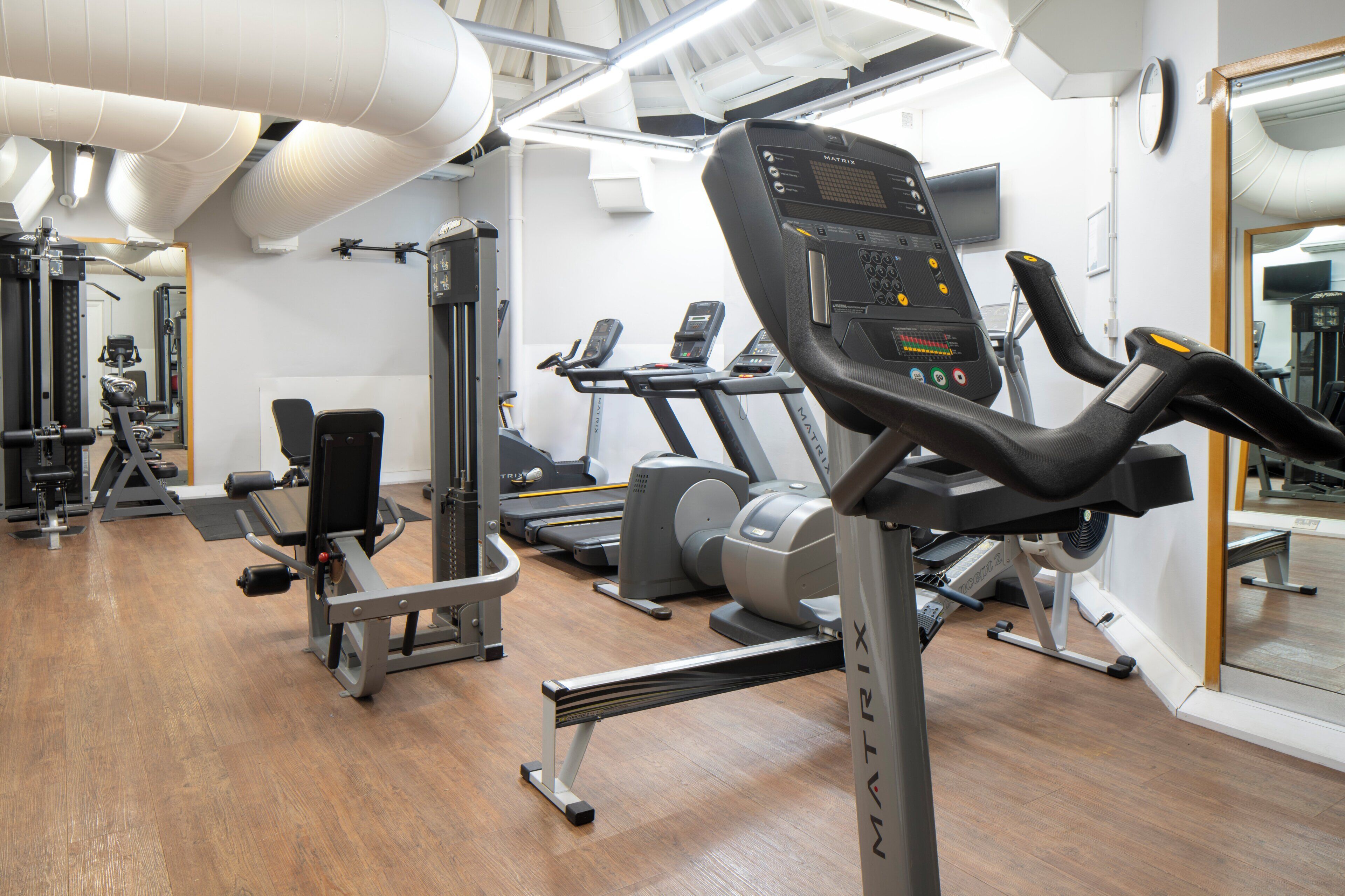 A gym with treadmills, weight machines, and a mirrored wall.