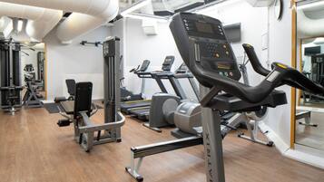 A gym with treadmills, weight machines, and a mirrored wall.