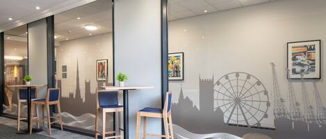 A modern office space with glass partitions, wooden chairs, and tables.