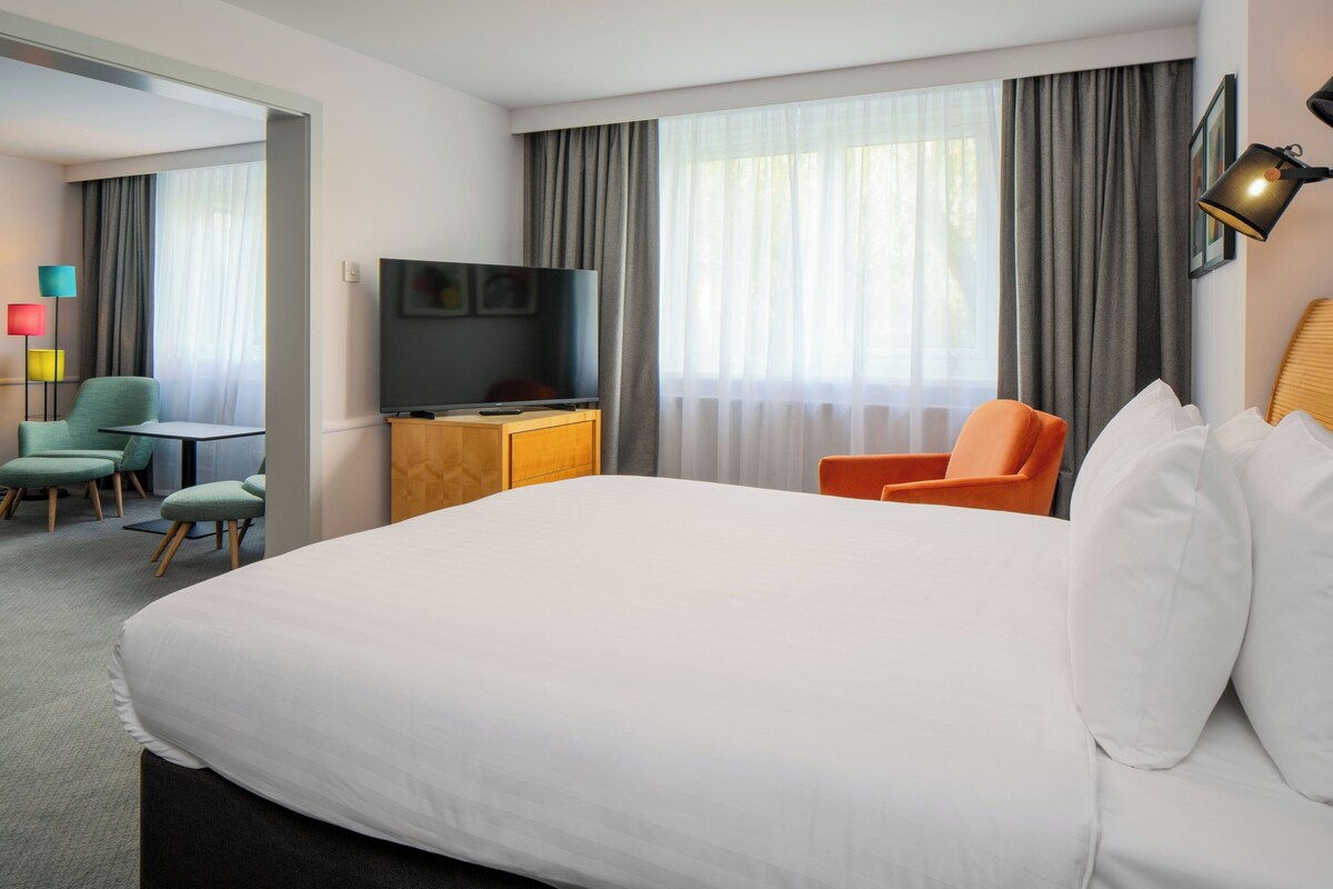 Een hotelkamer met een groot bed, een televisie, een bureau en twee stoelen.