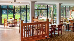 A spacious dining area with large windows, wooden furniture, and a patterned carpet. - Holiday Inn Bristol-Filton by IHG (Bristol)