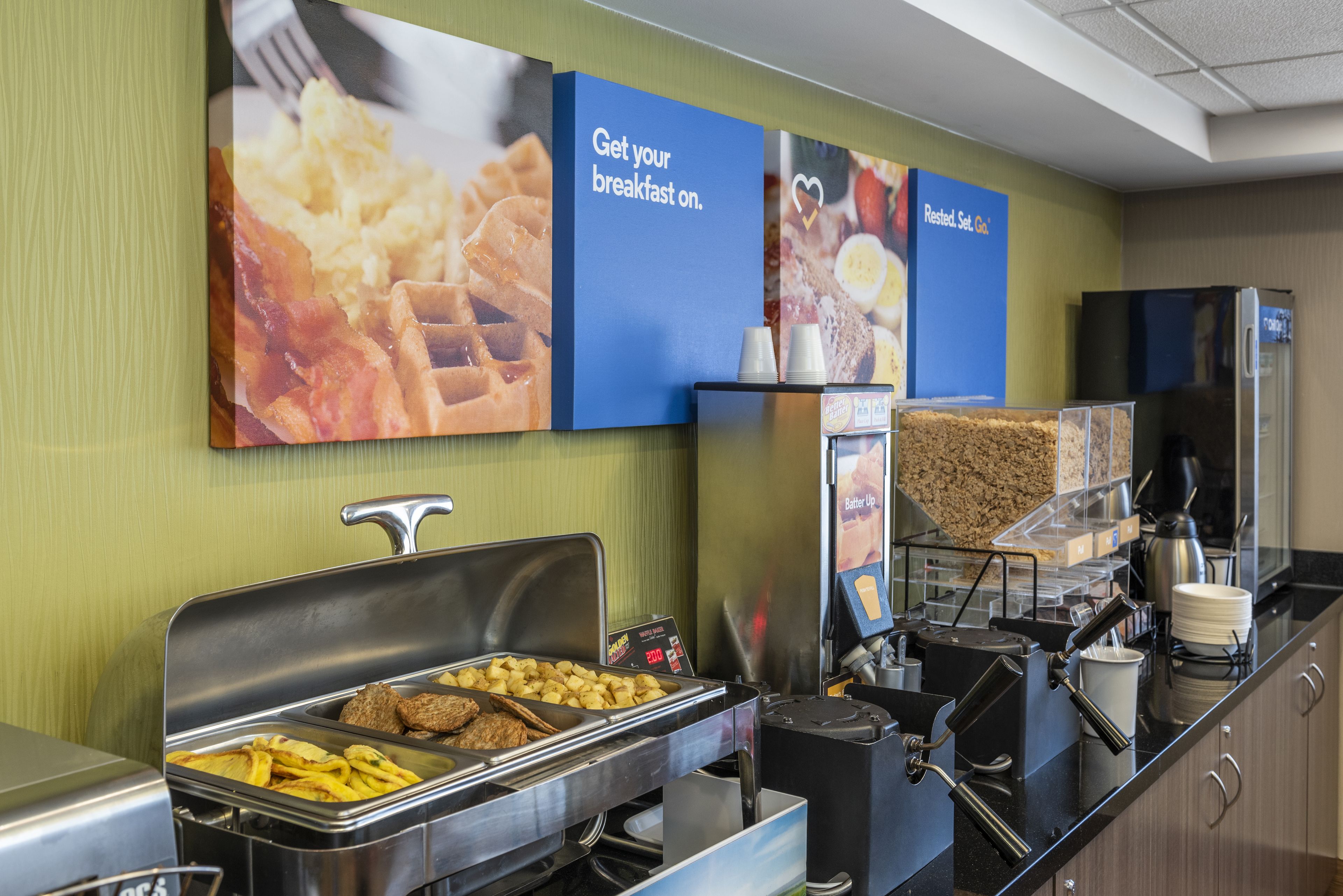 Een buffetgedeelte met diverse gerechten en een bord waarop staat 'Haal je ontbijt hier'