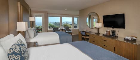 A hotel room with two beds, a desk, a television, and a view of the outdoors.