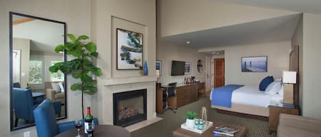 A hotel room with a fireplace, a bed, a desk, and a seating area with a coffee table.