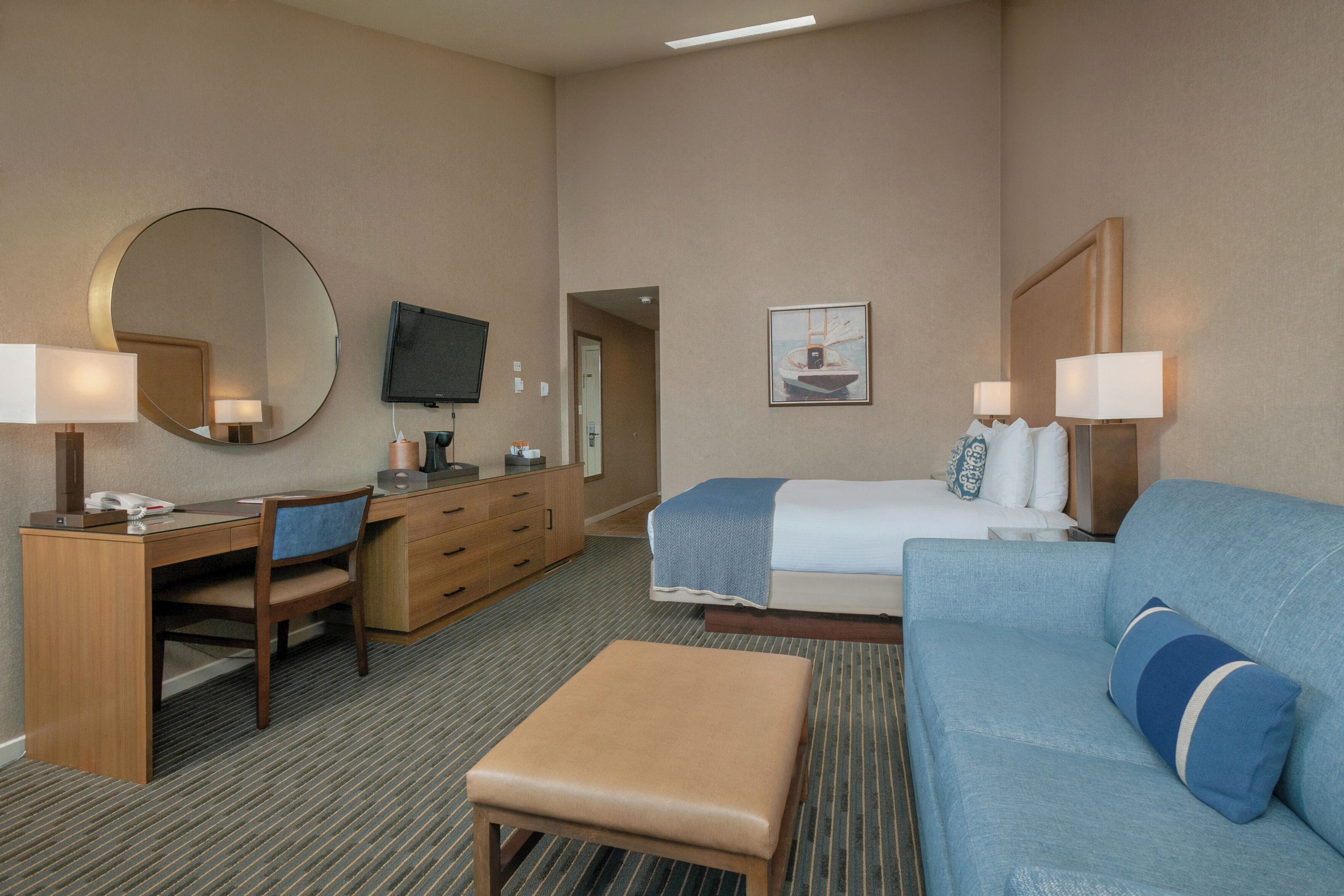 Een hotelkamer met een bed, een bureau, een stoel, een televisie en een bank.