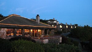 A building with a stone facade, large windows, and a flat roof with lights. - The Inn at the Tides (Bodega Bay)