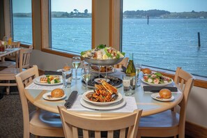 A dining table with seafood dishes, wine glasses, and a view of the water.