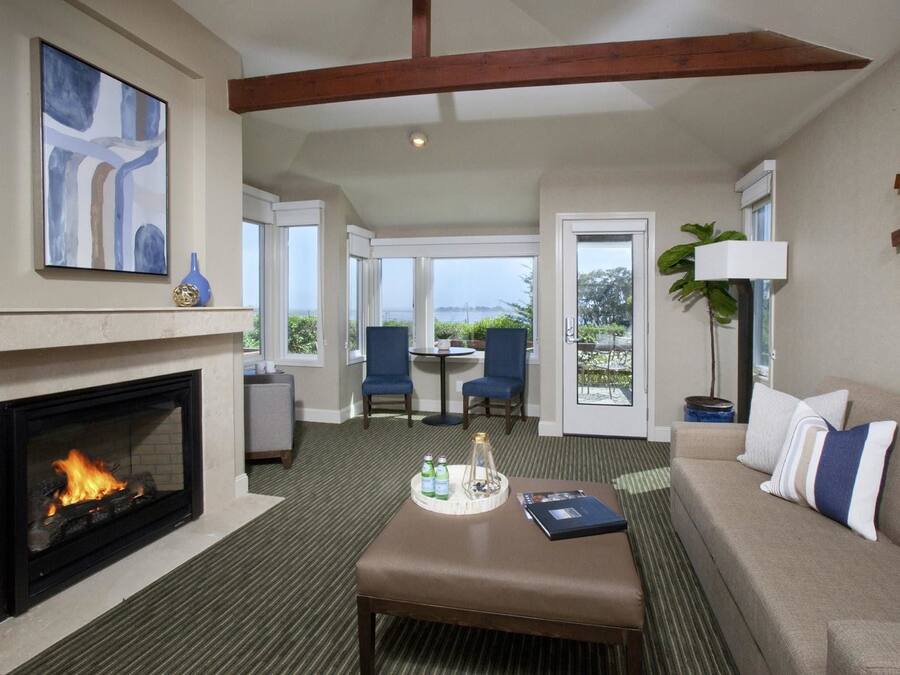 A hotel room with a fireplace, a sofa, a coffee table, and a view of the outdoors.