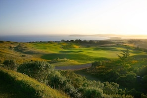 A golf course with a view of the ocean and distant land.