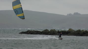 Una persona practicando windsurf en un cuerpo de agua, con una cometa grande.