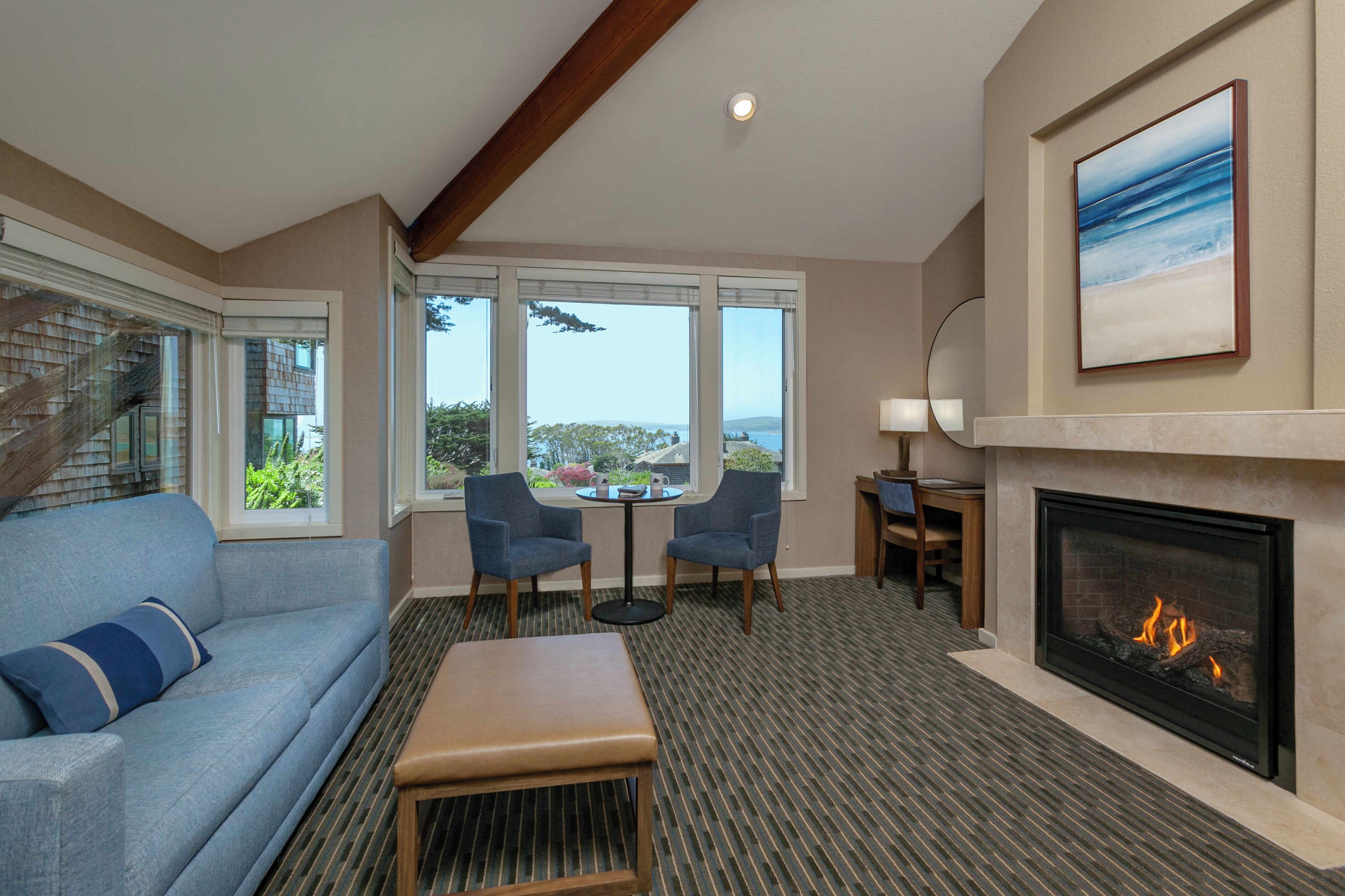 A living room with a fireplace, a sofa, two armchairs, a coffee table, and a view of the outdoors.