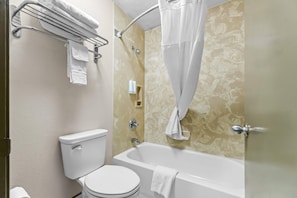 Une salle de bain équipée de toilettes, d’une baignoire et d’un rideau de douche.